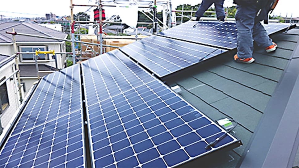 設置スタッフが屋根に太陽光発電パネルを設置している様子